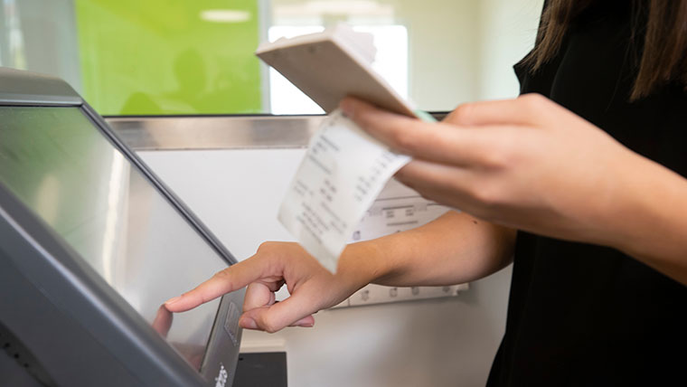 A hospitality student types a customer's bill and credit card information onto a computer screen while working at Carrie's Cafe.